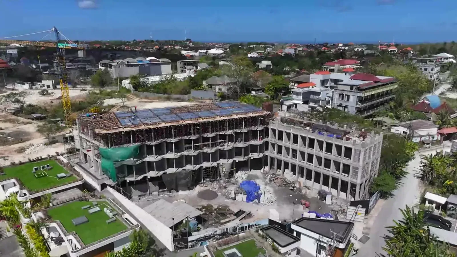Ardhana Residence under construction in Ungasan, from the HQC drone: the hotel frame, a tower crane and the Bukit rooftops running to the sea