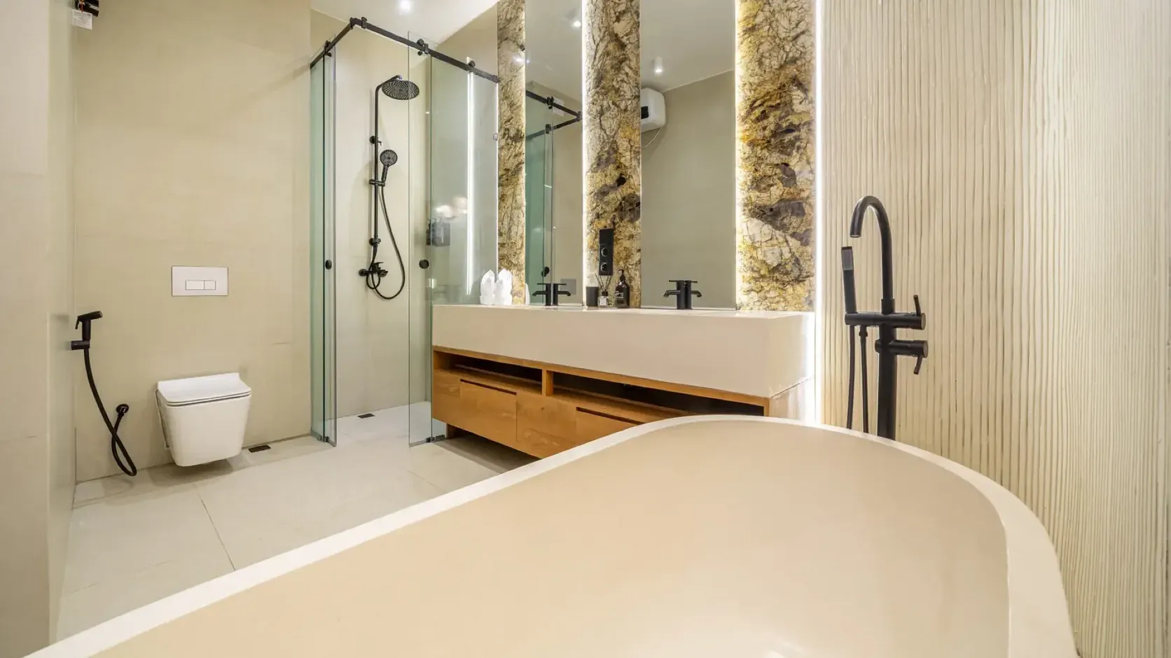 Finished bathroom in an HQC residence with a glass walk-in shower, a lit double vanity on timber drawers and a freestanding bath in the foreground