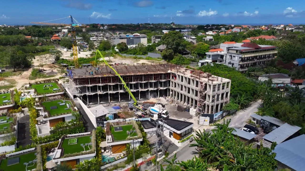 The Ardhana hotel frame rising beside the completed villas, from the air